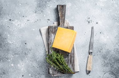 Tahta kesme tahtasındaki bıçaklı sert peynir. Parmesan peyniri. Gri arka plan. Üst görünüm