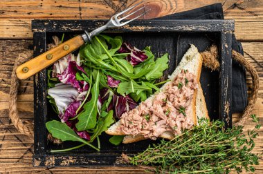 Peynirli ton balıklı sandviç, marul ve roka. Ahşap arka plan. Üst görünüm