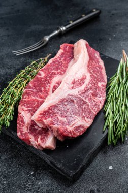 Çiğ Striploin bifteği ya da New York bifteği kesimi. Siyah arka plan. Üst görünüm
