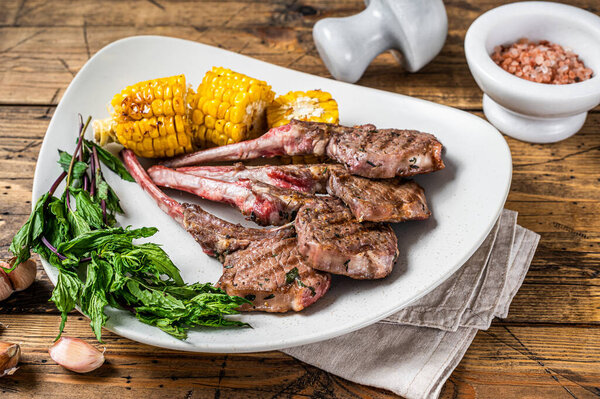 Жареная баранина отбивает стейки в тарелке с кукурузой и помидорами. деревянный фон. Вид сверху