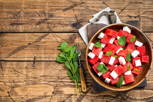 Zomer Watermeloen Salade met feta kaas en munt in een houten bord. Houten achtergrond. Bovenaanzicht. Kopieerruimte — Stockfoto