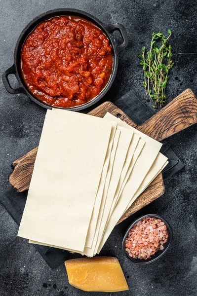 Сырье Различные ингредиенты для приготовления итальянской лазаньи на кухонном столе. Чёрный фон. Вид сверху — стоковое фото