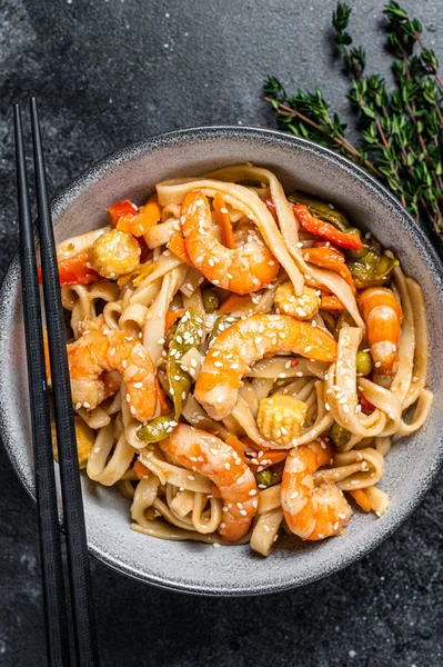 Roerbak udon zeevruchten noedels met garnalen in een kom. Zwarte achtergrond. Bovenaanzicht — Stockfoto