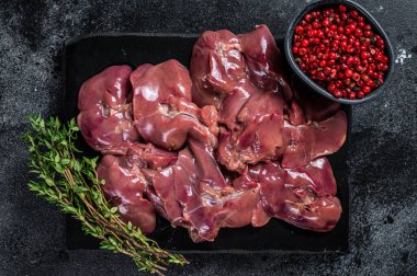 Mermer tahtada kekik ile çiğ tavuk ciğeri eti. Siyah arka plan. Üst görünüm