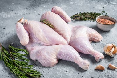 Çiğ spatchcock tavuk eti, sarımsak ve kekik. Gri arka plan. Üst görünüm