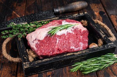 Tahta tepside bıçakla kesilmiş çiğ et eti. Koyu ahşap arka plan. Üst görünüm