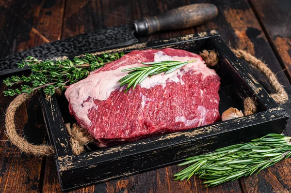 Rauw vlees van rundvlees gesneden op een houten dienblad met mes. Donker houten achtergrond. Bovenaanzicht — Stockfoto
