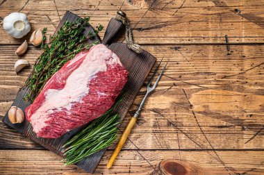 Taze çiğ et eti, ahşap bir tahtanın üzerinde otlarla kesilmiş. Ahşap arka plan. Üst Manzara. Boşluğu kopyala