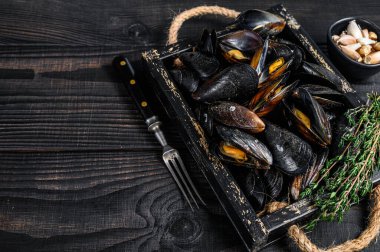 Kabuklu midyeler ahşap bir tepside otlarla birlikte. Siyah ahşap arka plan. Üst Manzara. Boşluğu kopyala