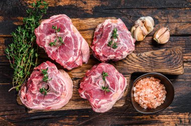 Satırla kasap tahtasında çiğ koyun eti. Koyu ahşap arka plan. Üst görünüm