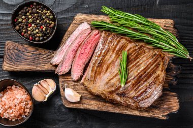 Mangalda ızgara et ya da ahşap kesme tahtasının üzerinde biftek. Siyah ahşap arka plan. Üst görünüm
