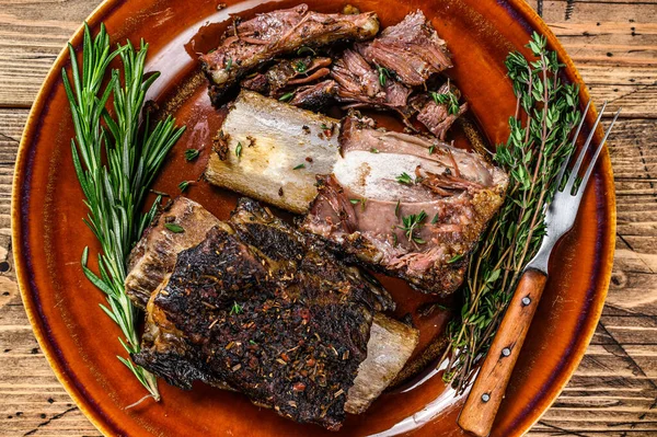 Grilled short beef ribs with thyme on a rustic plate. wooden background. Top view