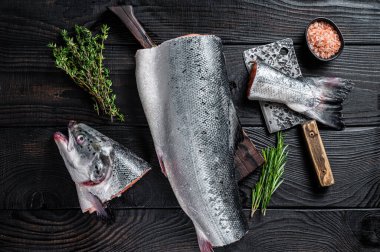 Ahşap kesme tahtasındaki çiğ somon balığı ve şef satır. Kara tahta arka plan. Üst görünüm