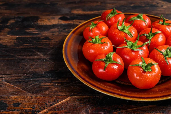 Röda mogna tomater på rustik tallrik. Mörk Trä bakgrund. Högst upp. Kopiera utrymme — Stockfoto