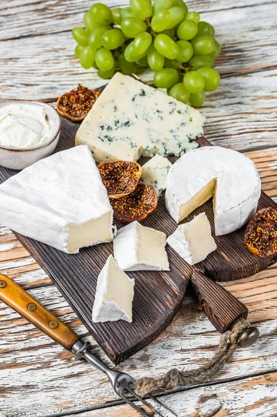 Tábua de queijo com brie, Camembert, Gorgonzola e queijo cremoso azul. Fundo de madeira branco. Vista superior — Fotografia de Stock