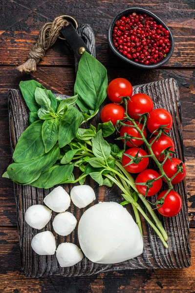 Mozzarella cheese, basil and tomato cherry on wooden board, Ingredients for Caprese salad. Dark wooden background. Top view — Stock Photo, Image