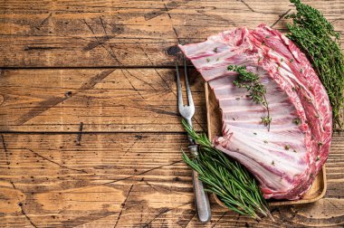 Ahşap tepside otlu kuzu pirzola rafı. Ahşap arka plan. Üst Manzara. Boşluğu kopyala