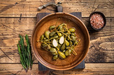 Tahta bir tabakta sirke içinde tuzlanmış kapari. Ahşap arka plan. Üst görünüm