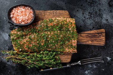 Gravlax ahşap tahtada dereotlu ve tuzlu somonu tedavi etti. Siyah arka plan. Üst görünüm