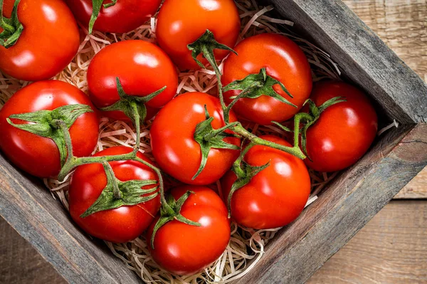 Mogna röda tomater i en trälåda. Trä bakgrund. Ovanifrån — Stockfoto