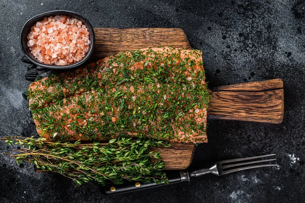 Gravlax botad lax med dill och salt på träskiva. Svart bakgrund. Ovanifrån — Stockfoto