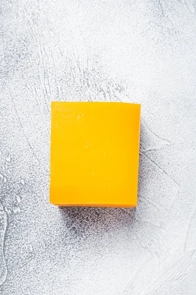 Blocco di formaggio Cheddar su un tavolo da cucina. Sfondo bianco. Vista dall'alto — Foto Stock