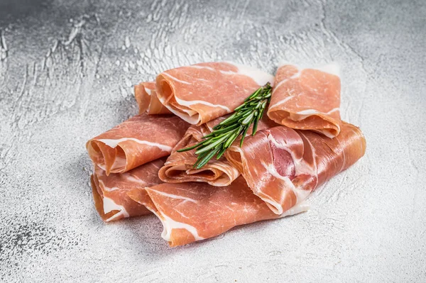 Italská šunka prosciutto crudo parma na stole. Bílé pozadí. Pohled nahoru — Stock fotografie