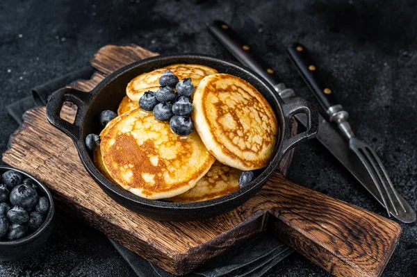 Pancake dengan blueberry segar dan sirup maple dalam panci. Latar belakang hitam Tampilan Atas — Stok Foto