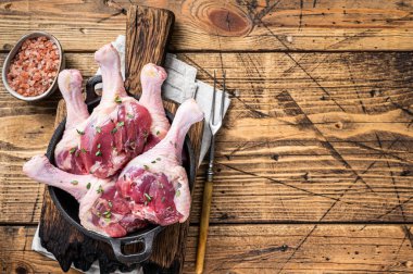 Tavada çiğ ördek budu ve otlar. Ahşap arka plan. Üst Manzara. Boşluğu kopyala