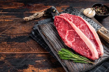 Kasap panosunda et satırlı çiğ sığır eti bifteği. Karanlık woden arka plan. Üst Manzara. Boşluğu kopyala