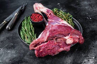 Kemiğin üzerinde çiğ kuzu eti ve otlar. Siyah arka plan. Üst görünüm