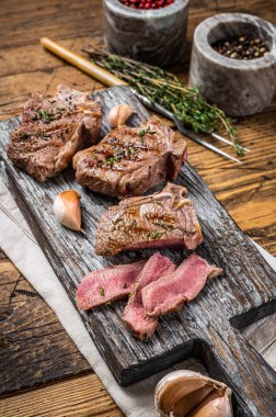 Barbekü kuzu fileto bifteği, ahşap bir tahtanın üzerinde otlarla kavrulmuş pirzola. Ahşap arka plan. Üst görünüm