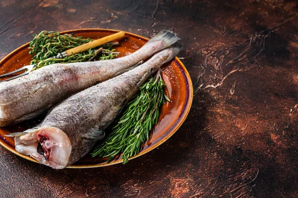 Bacalhau cru não cozido ou bacalhau em prato rústico com ervas e garfo. Fundo escuro. Vista superior. Espaço de cópia — Fotografia de Stock