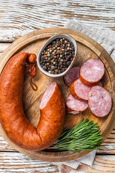 Bavarian Smoked sausage on a wooden board with herbs. White wooden background. Top view — Stock Photo, Image