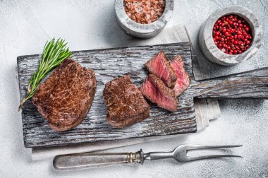 Kızarmış fileto mignon ya da ahşap kesme tahtasında bonfile biftek. Beyaz arka plan. Üst görünüm