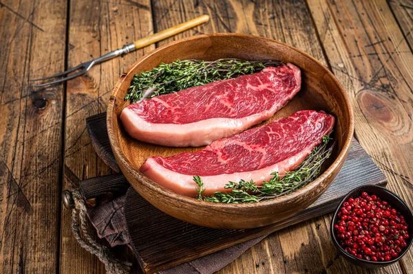 未煮熟的生牛腰肉盖牛肉蒸肉在一个木制盘子里与香草。沃登背景。顶部视图 — 图库照片