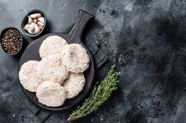 Pişmemiş çiğ köfte pirzolası ahşap kesme tahtasının üzerinde otlarla birlikte. Siyah arka plan. Üst Manzara. Boşluğu kopyala