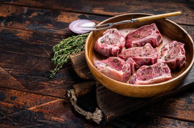 Çiğ kuzu fileto kaburga pirzola, ahşap tabakta biftek ve şifalı otlar. Ahşap arka plan. Üst Manzara. Boşluğu kopyala