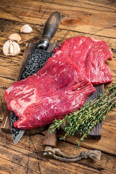 Filetes de carne cruda de flanco en una tabla de cortar carnicero con cuchillo. fondo de madera. Vista superior —  Fotos de Stock