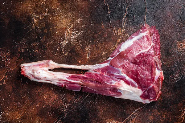 Carne cruda di coscia di capra sull'osso. Sfondo scuro. Vista dall'alto — Foto Stock