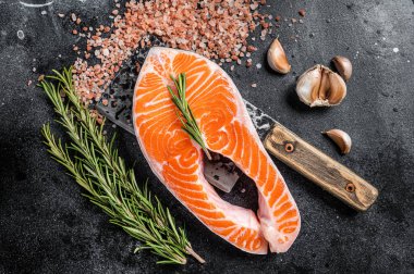 Et satırıyla kasap masasında çiğ somon balığı bifteği. Siyah arka plan. Üst görünüm