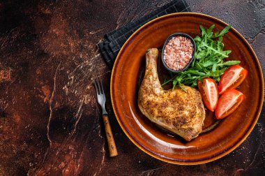 Kümes hayvanları tabağı. Kızarmış tavuk bacağı ve sebze salatası. Karanlık arka plan. Üst Manzara. Boşluğu kopyala