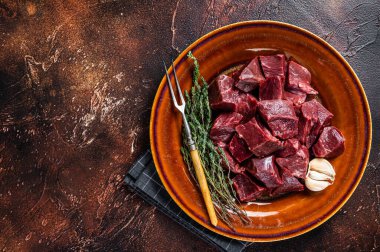 Sığır eti ya da çiğ kalbi kırsal bir tabakta otlarla kes. Karanlık arka plan. Üst Manzara. Boşluğu kopyala