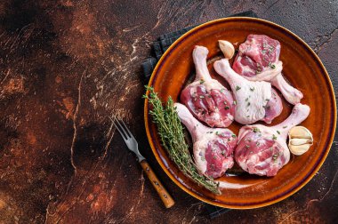 Çiğ kümes hayvanları, ördek bacakları kırsal bir tabakta otlarla birlikte. Karanlık arka plan. Üst Manzara. Boşluğu kopyala