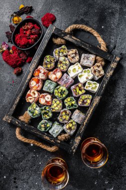 Türk Lokum 'u, fındıklı ve siyah çaylı oryantal tatlılar. Siyah arka plan. Üst görünüm