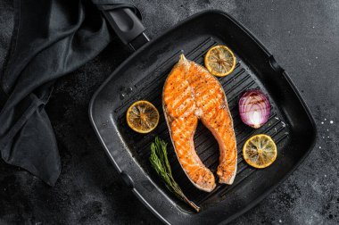 Izgarada otlarla ızgara edilmiş somon balığı bifteği. Siyah arka plan. Üst görünüm