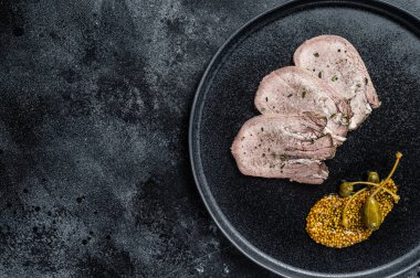 Bir tabakta haşlanmış dil dilimleri. Siyah arka plan. Üst Manzara. Boşluğu kopyala