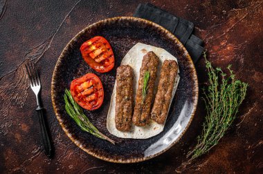 Izgara Urfa şiş kebap ve domates. Karanlık arka plan. en üstteki görünüm