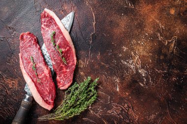 Pişmemiş çiğ sığır filetosu ya da kasap bıçağında biftek. Karanlık arka plan. Üst Manzara. Boşluğu kopyala