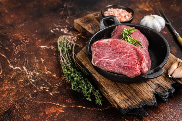 Tavada çiğ sığır fileto eti ve otlar. Karanlık arka plan. Üst Manzara. Boşluğu kopyala